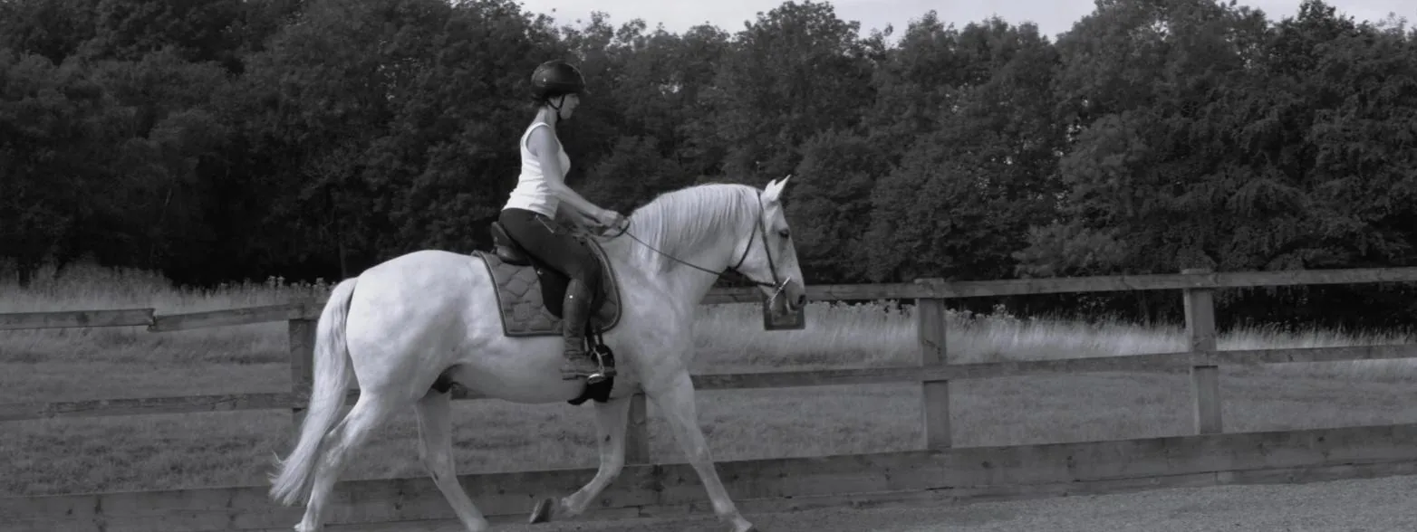 Jennifer Castagna riding a grey horse in an outdoor arena